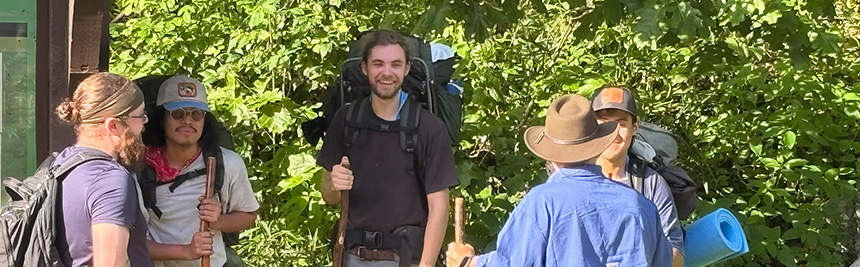 Team of hikers standing together on a sunny trail, sharing and connecting outdoors as part of Joshua Expeditions evangelism focus